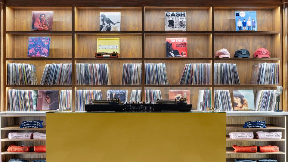 Record store interior with vinyl records on shelves and a yellow reception desk.